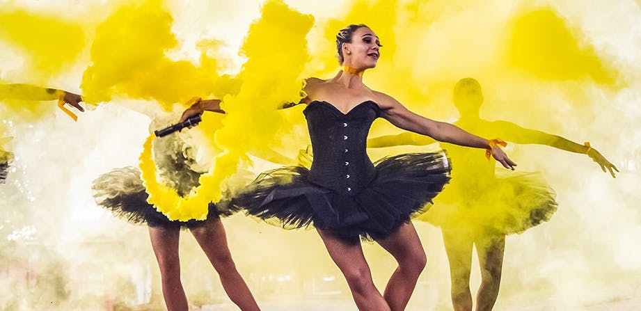 Ballerinas dancing around yellow smoke in black tutus
